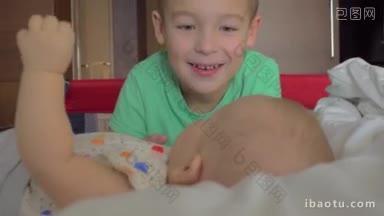 一个穿绿色t恤的男孩正在看他6个月大的小妹妹，她正躺在一张